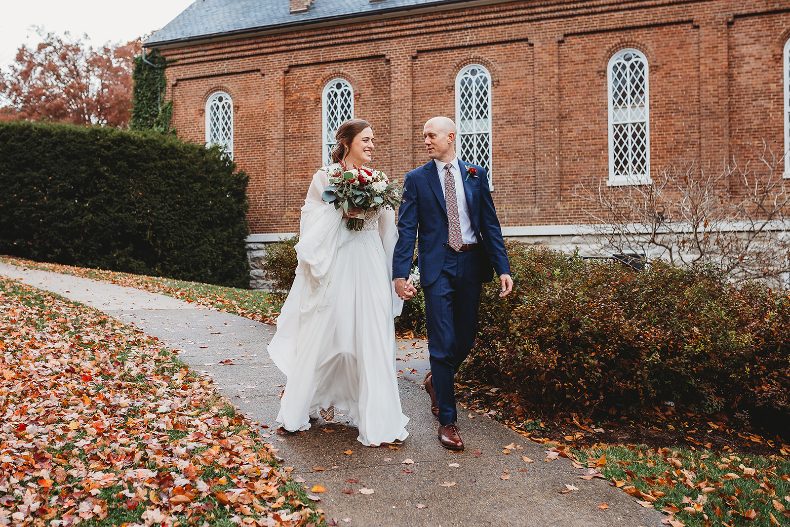 After exchanging vows, the bride and groom walk happily alongside their historic wedding venue in Lexington, Virginia, University Chapel.